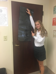 Sophomore Quinn Kaloper exemplifies impeccable technique when putting up the black poster in order to prevent the intruder from seeing the students inside the classroom. 